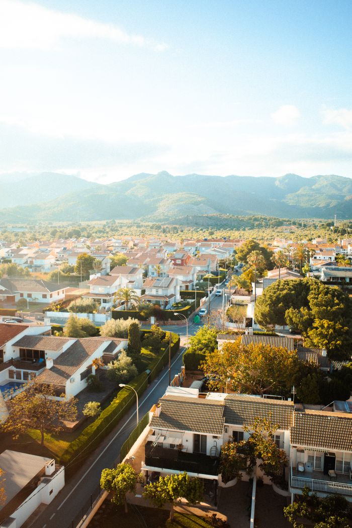 Aerial view of suburban Benicàssim, Spain, showcasing picturesque mountains and lush greenery.